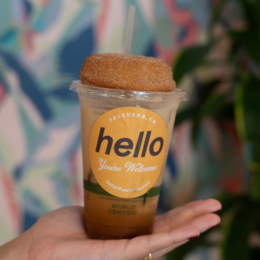 Iced coffee drink topped with a cinnamon donut in a cup labeled hello, from a Pasadena café